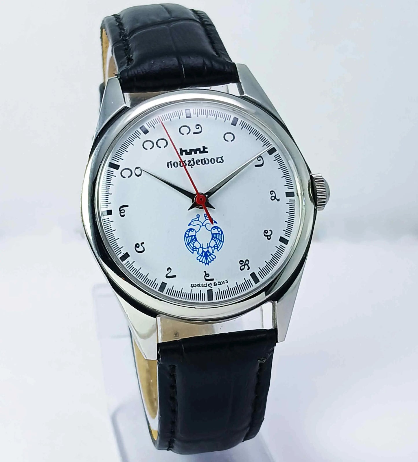 Wristwatch with black leather strap and white dial on a light gray background