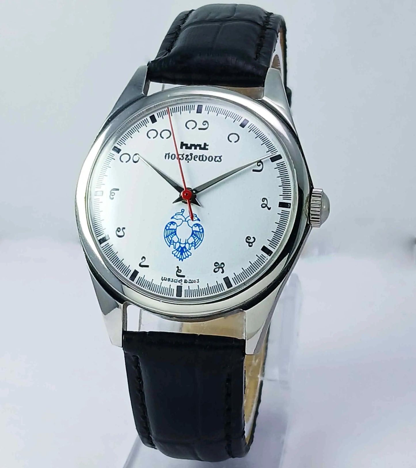 Watch with black leather strap and white face on a light gray background