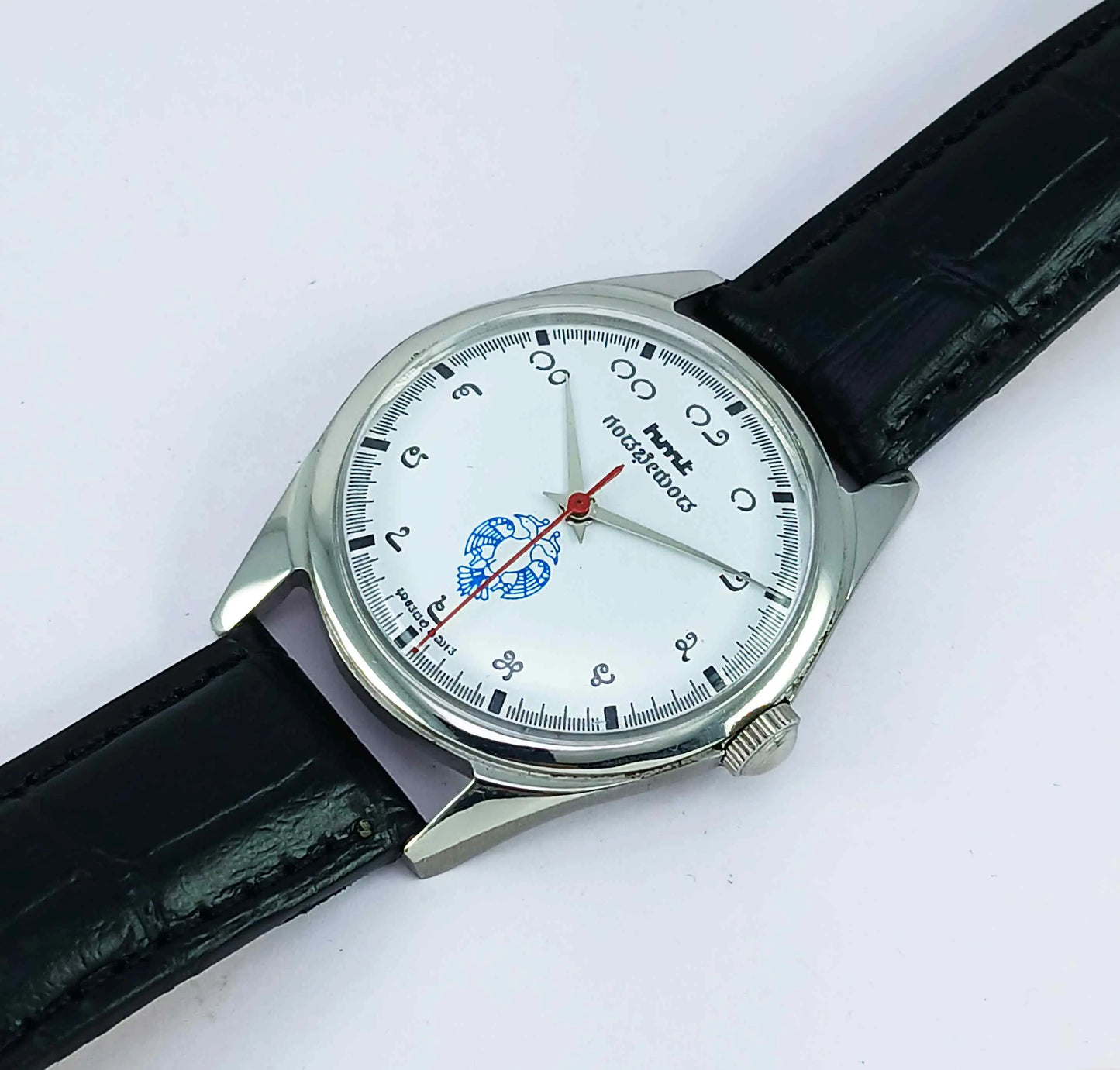 Wristwatch with black strap and white face on a light gray background