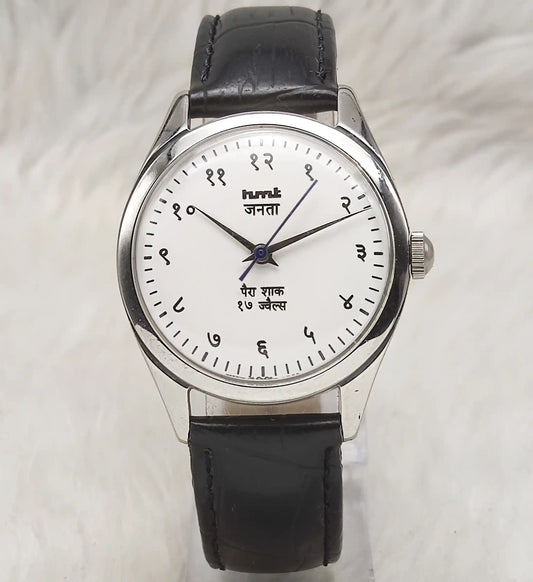 Wristwatch with black leather strap and white dial on a light gray background